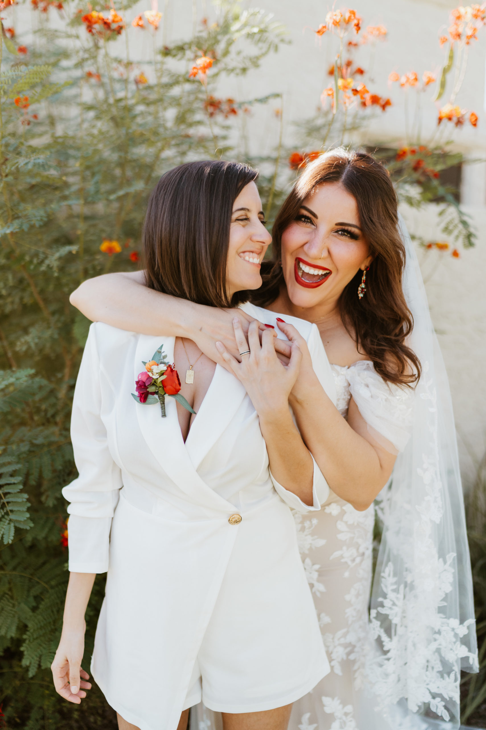 Two brides embracing each other facing toward the cameras
