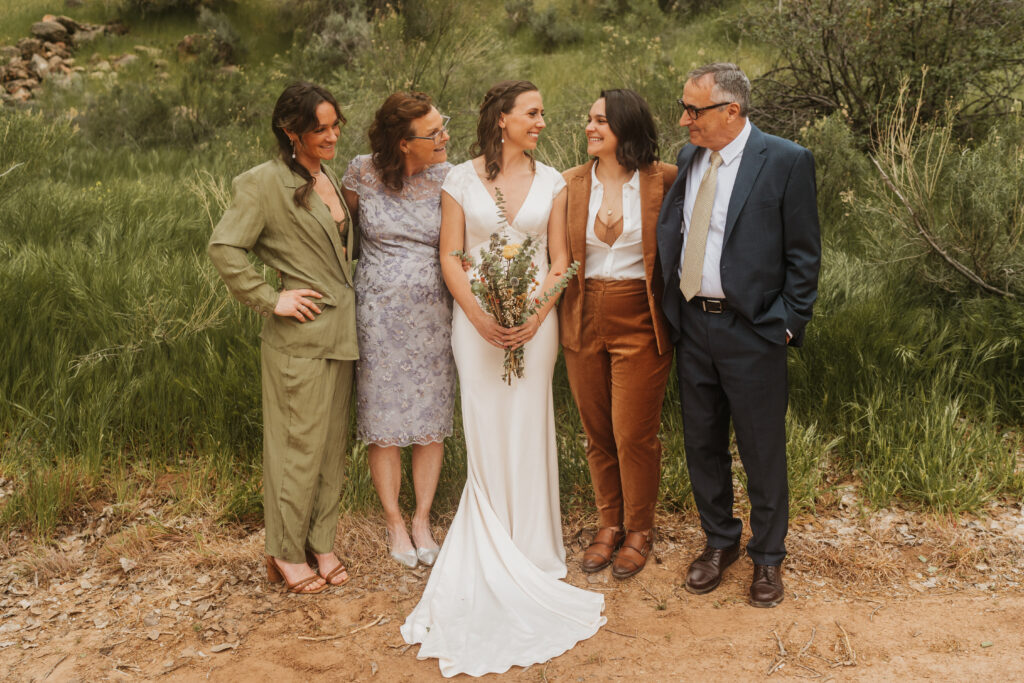Two brides with one of their mom and dad and sister pose for family portraits on their wedding day. 